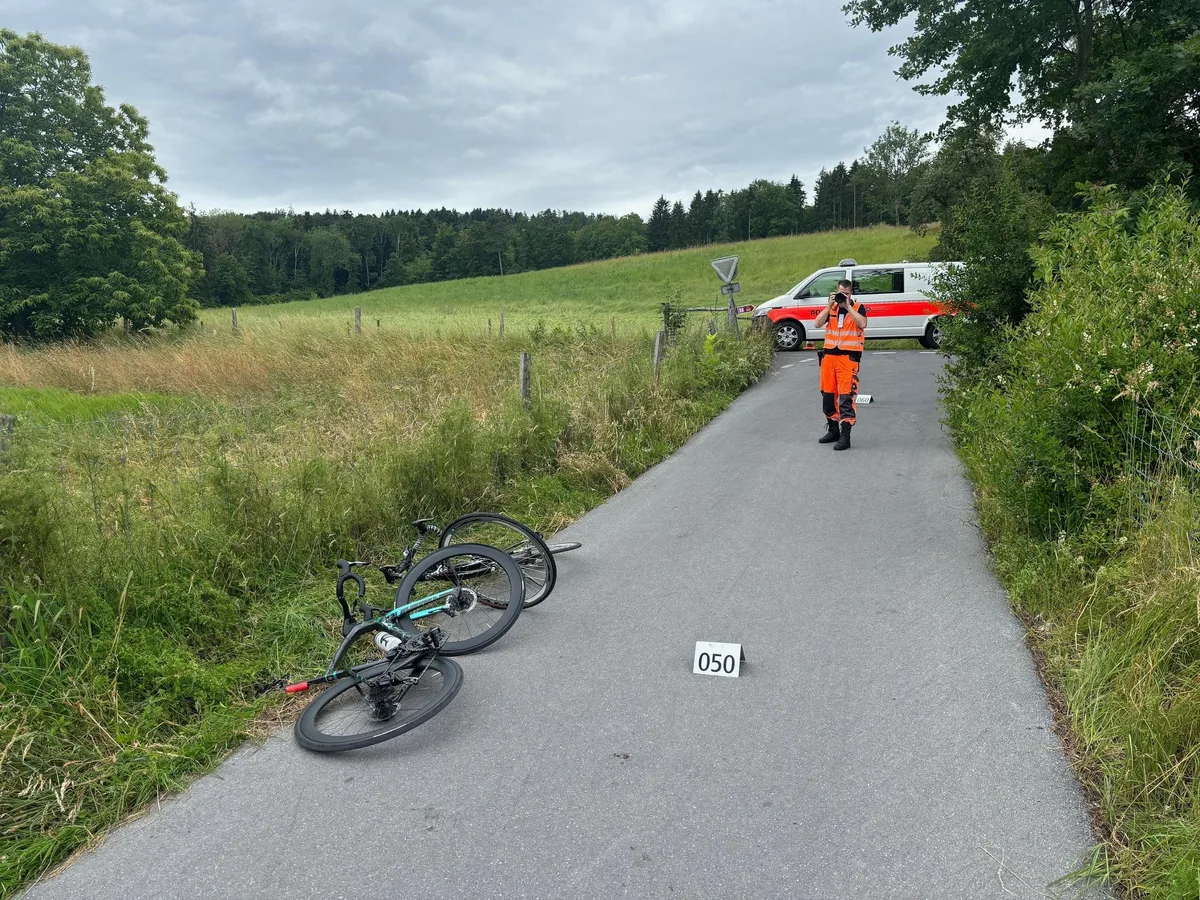 Wie es zum Unfall in Maur kam, müssen die Polizei und die Staatsanwaltschaft jetzt abklären. Man sieht zwei Rennvelos auf einem Weg und einen Polizisten und ein Polizeiauto.